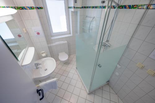 a bathroom with a shower and a toilet and a sink at Strandruh Apartments in Binz