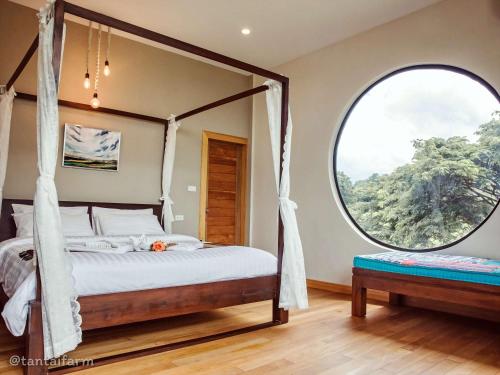 a bedroom with a canopy bed and a large window at Tantai Eco Farm Stay At Khao Yai in Ban Sap Noi