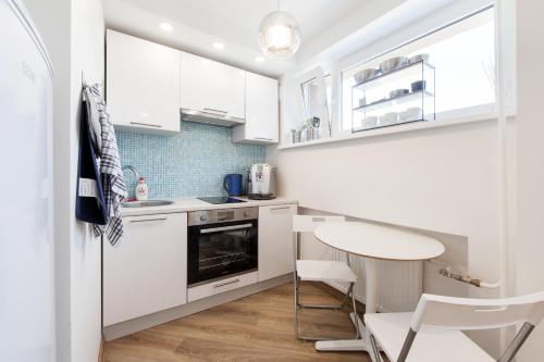 a kitchen with white cabinets and a table and chairs at Nordic design apartment in Tallinn