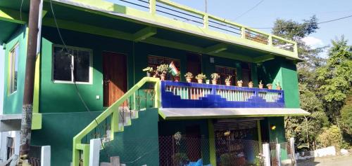 a green building with a balcony with plants on it at Greenery Homestay in Darjeeling
