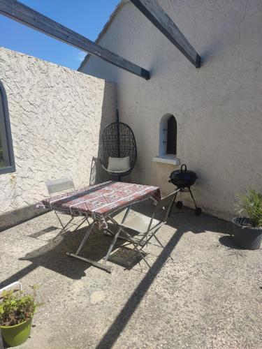 a patio with a table and a chair and a grill at Studio en pleine campagne in Le Thor
