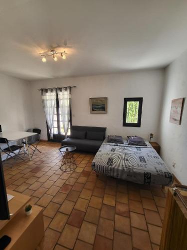 a bedroom with a bed and a couch and a table at Studio en pleine campagne in Le Thor