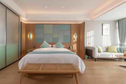 um quarto com uma cama grande e um sofá em SSAW Boutique Hotel Zhijiang em Hangzhou