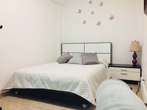 1 dormitorio con 1 cama con sábanas blancas y mariposas en la pared en Department, Studio Type Excellent Location, en Ciudad de México