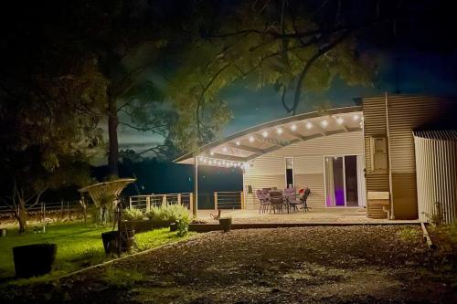 a house with a deck with a table and chairs at The Shedhouse at Milbrodale Farm in Bulga