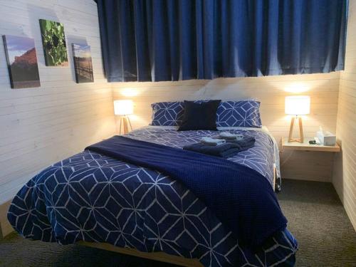 een slaapkamer met een blauw bed en 2 lampen bij The Shedhouse at Milbrodale Farm in Bulga