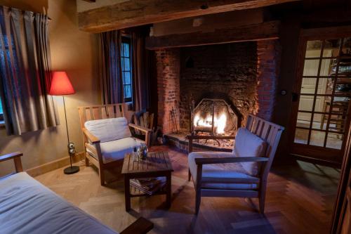 a bedroom with a fireplace and two chairs and a bed at Cottage les forières in Saint-Honoré