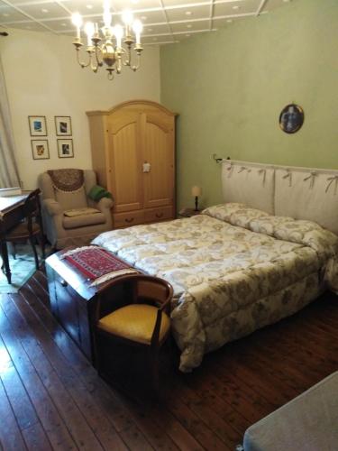 a bedroom with a bed and a chair and a chandelier at Dimora Giosafatti in Ascoli Piceno
