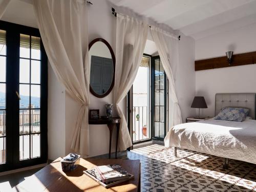 a bedroom with a bed and a mirror and windows at Mesón La Hospedería in Cómpeta