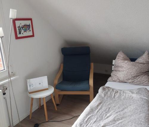 um quarto com uma cadeira azul ao lado de uma cama em Pension Limone Ferienwohnung 2 em Neu Lindenberg