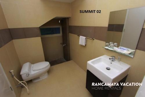 a bathroom with a white toilet and a sink at R Hotel Rancamaya in Bogor