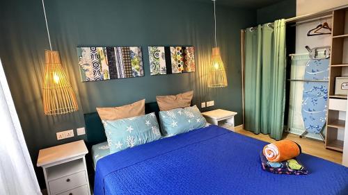 una camera da letto con un letto blu con cuscini blu di Les Cerisiers - Beach Apartment with Pool, Few Steps to the Beach a Flic-en-Flac