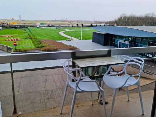 a table and two chairs on a balcony with a view of a field at Appartement 't Pand in Nieuwpoort