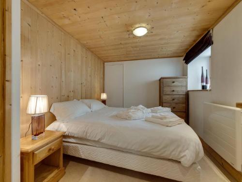 - une chambre avec un lit blanc et un mur en bois dans l'établissement L'Aigle du Laisinant duplex de 90m2 à Val d'Isere, à Le Fornet