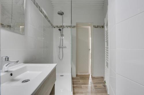 a white bathroom with a sink and a shower at H&ocirc;tel De France in Angers