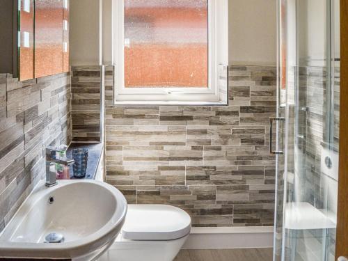 uma casa de banho com um lavatório, um WC e uma janela. em Peace Haven em Gorleston-on-Sea