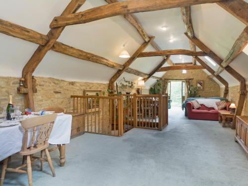 a living room with wooden ceilings and a dining room at Flowers Barn in Daglingworth