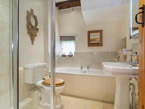 uma casa de banho com um WC, um lavatório e uma banheira em Flowers Barn em Daglingworth