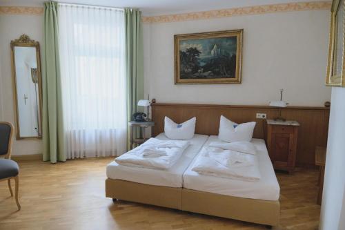 a bedroom with a bed with white pillows on it at Jahrhunderthotel Leipzig in Leipzig