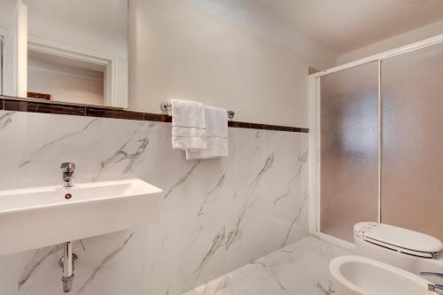 a white bathroom with a sink and a toilet at Ca' Riza in Venice