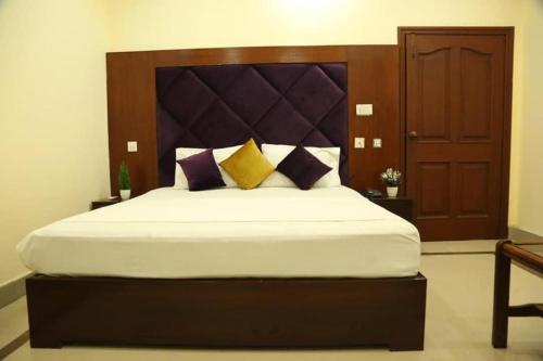 um quarto com uma cama grande com almofadas roxas e amarelas em Hotel Royal Luxury Multan em Multan