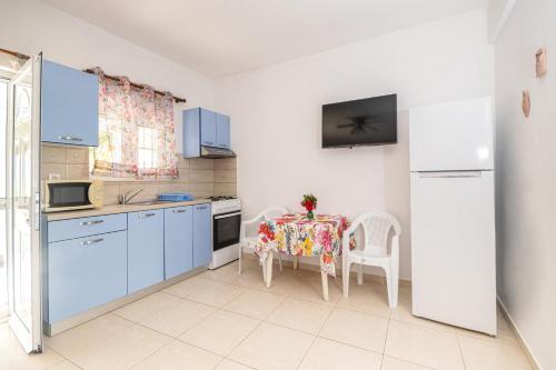 kuchnia z niebieskimi szafkami i stołem z krzesłami w obiekcie Salora Studio-Apartments w mieście Archangelos
