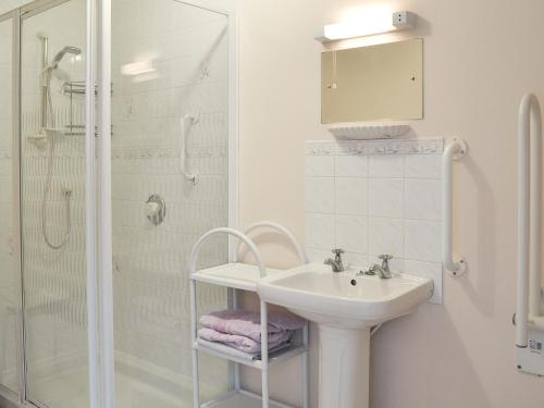 a white bathroom with a sink and a shower at The Annexe in Newchurch