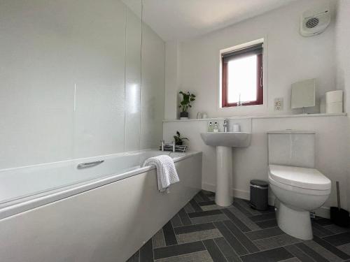 a white bathroom with a toilet and a sink at Ceol Na Mara in Dornoch