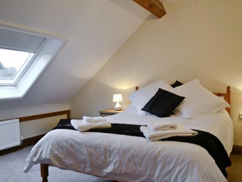 a bedroom with a bed with white sheets and a window at Yr Efail Argoed in Llandowror