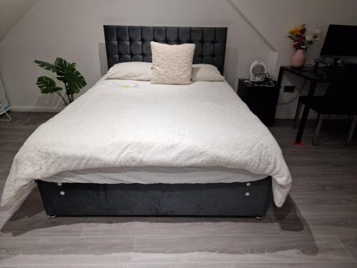 a bed with a white blanket and a black headboard at 32 in Ashford