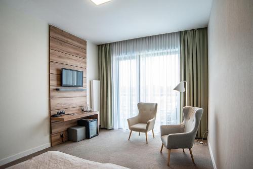 a hotel room with two chairs and a desk and a television at Hotel Bonifacio SPA&SPORT Resort in Sochocin
