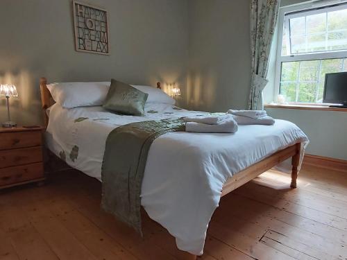 a bedroom with a bed with white sheets and a window at Bronhaul in Llanbrynmair