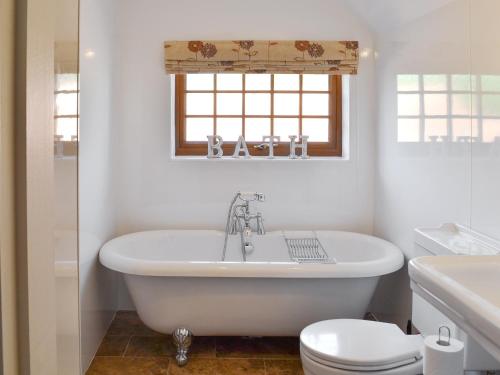 a white bathroom with a tub and a toilet at Boothby Cottage in Willoughby