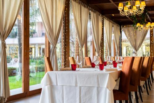 a dining room with a white table and chairs and windows at Hotel Isola Sacra Rome Airport in Fiumicino