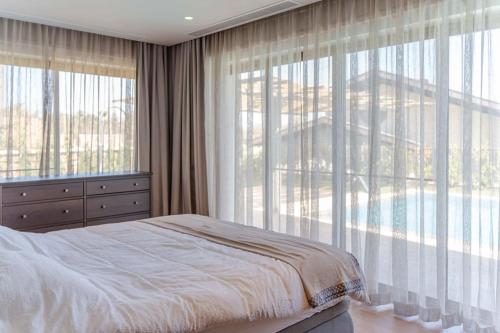 a bedroom with a bed and large windows with a pool at Enjoy playing golf, stay where luxury meets peace. in Bodrum City
