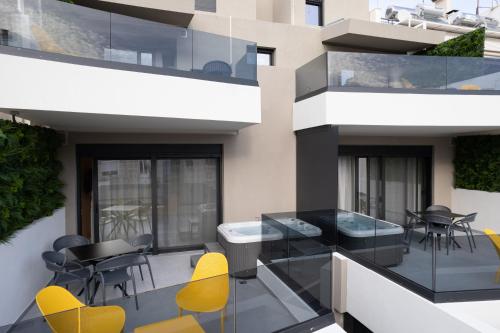 a balcony with yellow chairs and tables on a building at Incanto Boutique Suites - Neos Kosmos in Athens