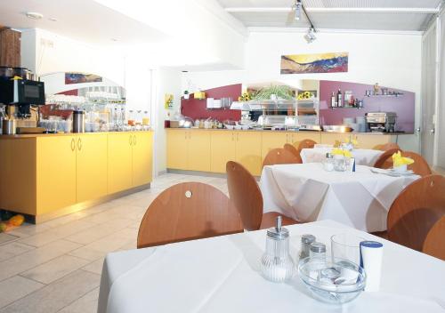 ゲッピンゲンにあるHotel Drei Kaiserbergeのテーブル2台と黄色のキャビネットが備わるレストラン