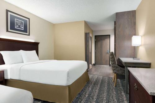 a hotel room with a bed and a desk at Travelodge by Wyndham Coffeyville in Coffeyville