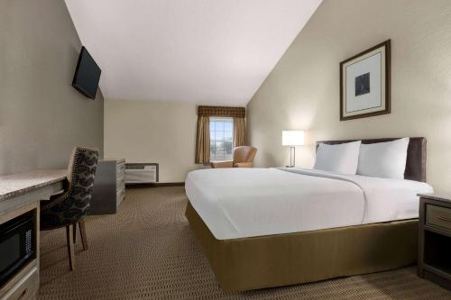 a hotel room with a large bed and a desk at Travelodge by Wyndham Coffeyville in Coffeyville