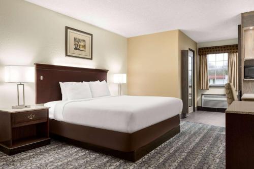 a hotel room with a large bed and a television at Travelodge by Wyndham Coffeyville in Coffeyville