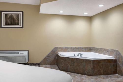 a bathroom with a bath tub and a bed at Travelodge by Wyndham Coffeyville in Coffeyville