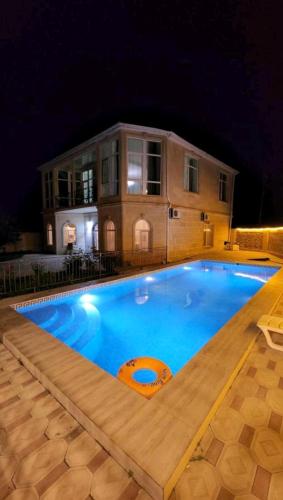 a swimming pool in front of a house at night at Holiday inn Adnan boutique hotel and pool in Gabala