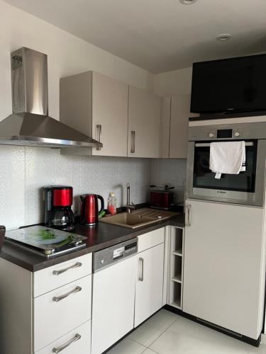 uma cozinha com armários brancos e um forno com placa de fogão em Pension-Geli em Monplaisir