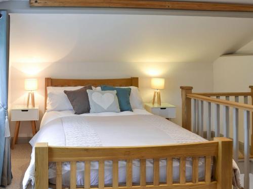 a bedroom with a wooden bed with two lamps at The Nest in Uny Lelant