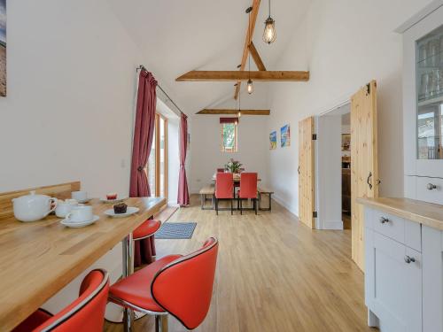 a kitchen and living room with red chairs and a table at The Coach House in Upwell