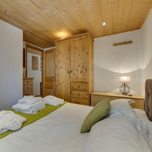 - une chambre avec un grand lit blanc et des plafonds en bois dans l'établissement Le Loup du Laisinant, à Le Fornet