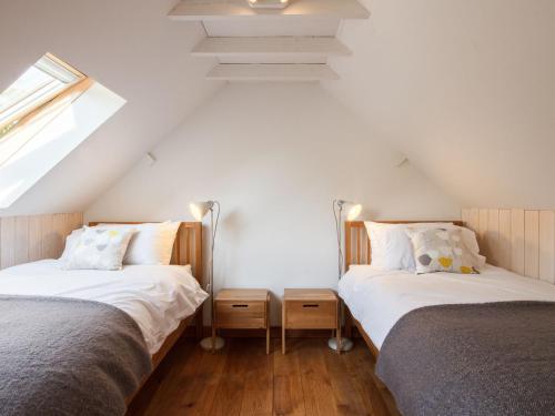 Schlafzimmer im Dachgeschoss mit 2 Betten und einem Fenster in der Unterkunft The Cider Barn in Flaxley