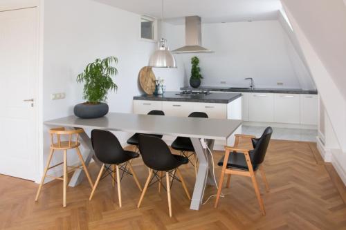 a white kitchen with a table and chairs at Canal House in Historic City Center Gouda in Gouda