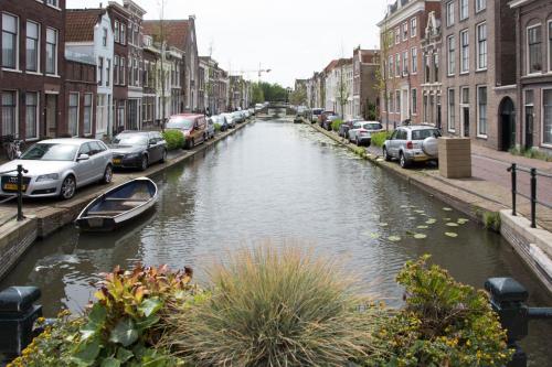 a canal in a city with parked cars and a boat at Canal House in Historic City Center Gouda in Gouda