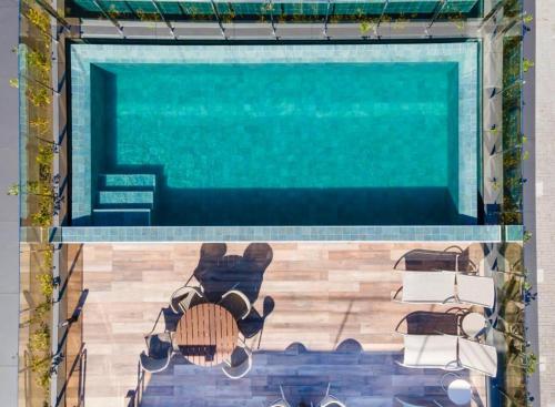 una piscina con 2 sillas y una mesa en Frente Mar Apartamento Luxuoso na praia de Cabo Branco, en João Pessoa